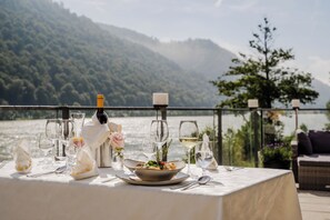 A table set for dining with a scenic lake view, a bottle of wine, and a candle.