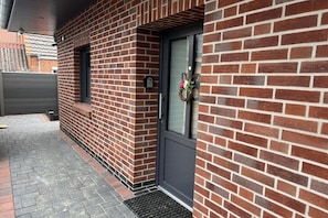 A brick exterior with a dark door, a small window, and a mailbox. - Holiday home in Pewsum with swimming pool (Pewsum)