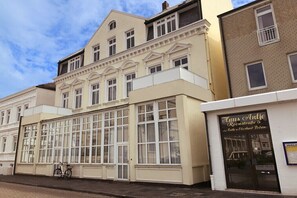 Ein Gebäude mit großen Fenstern, ein Fahrrad, das davor abgestellt ist, und ein Schild mit der Aufschrift 'Haus Antje'.