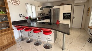 A kitchen with a central island, bar stools, a refrigerator, oven, and a microwave. - Charming villa with a private pool in the heart of the Var (La Motte)