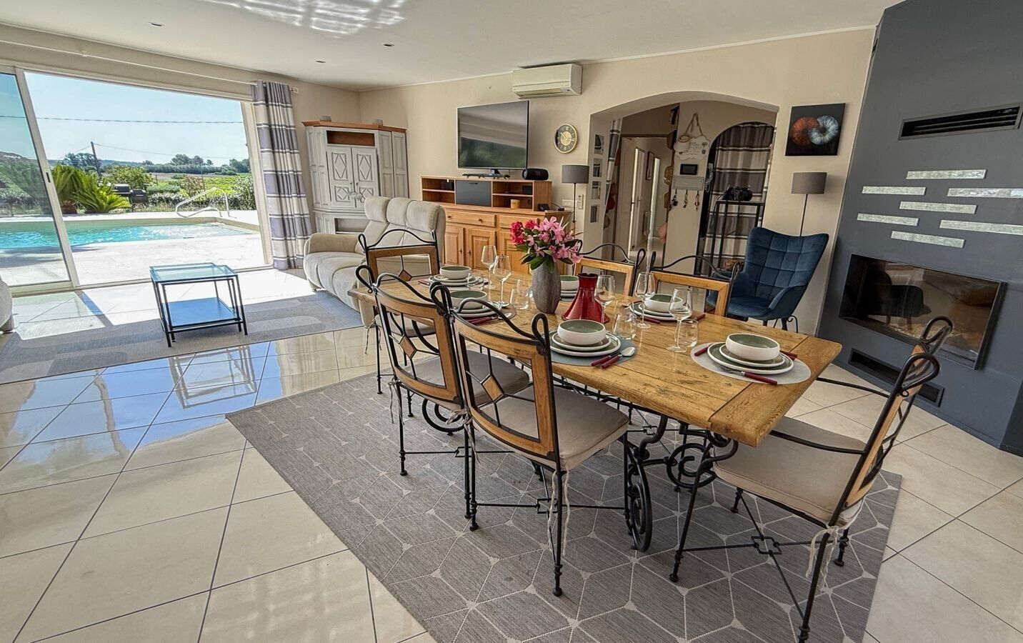A dining area with a wooden table, chairs, and a view of a swimming pool.
