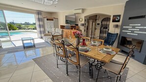 Zona pranzo con tavolo in legno, sedie e vista su una piscina.