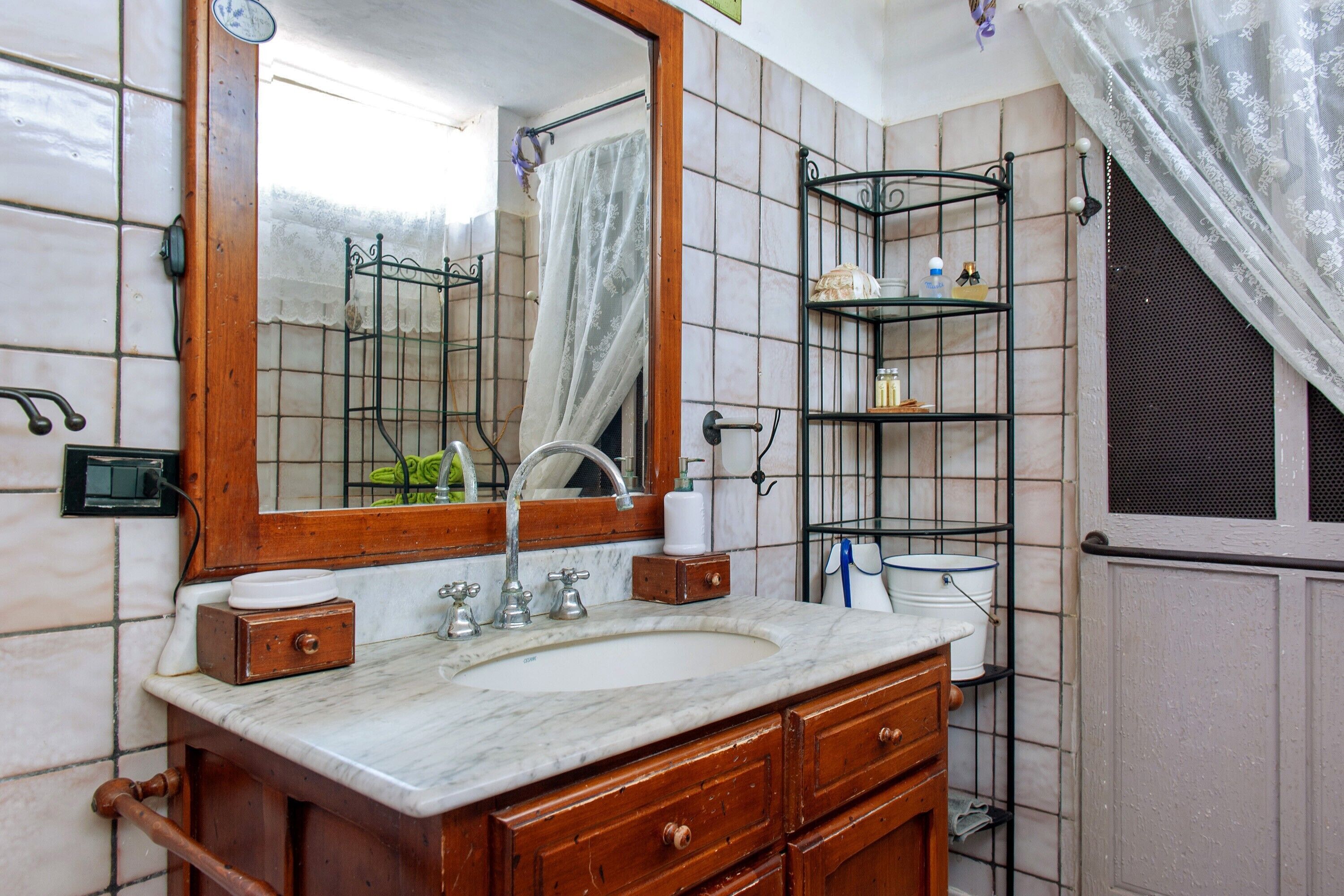 A bathroom with a marble sink, wooden vanity, and a mirror with a shower curtain.