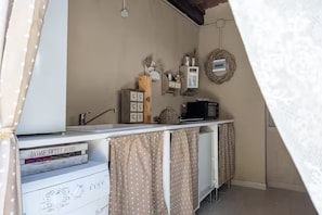 Een keuken met een wit aanrecht, een boek getiteld 'HOME SWEET HOME', een houten kast en een wandplank met decoratieve objecten.