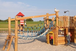 A wooden playground structure with a rope bridge, slides, and climbing areas. - Sea view in the Emma holiday home in Arngast (Varel-Dangast)
