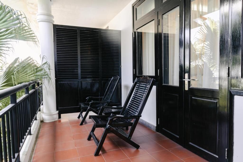 A balcony with two black chairs, a black door, and a white pillar.