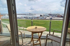 Ein Balkon mit Blick auf eine Marina, ein runder Holztisch und Korbstühle.