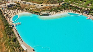 An aerial view of a resort with a large central pool, multiple smaller pools, and a variety of sun loungers and umbrellas.