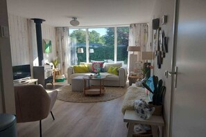 Ein Wohnzimmer mit einer Couch, einem Sessel, einem Couchtisch und einem Fernseher.