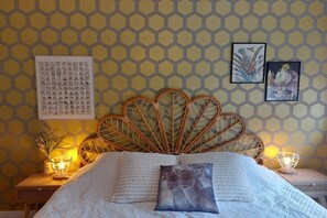 Ein Bett mit einem blattförmigen Kopfteil, eine Wand mit sechseckigem Muster und zwei gerahmte Kunstwerke.