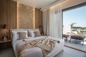 Een moderne slaapkamer met een groot bed, houten paneelwanden, uitzicht op de omgeving en een balkon met een tafel en stoelen.