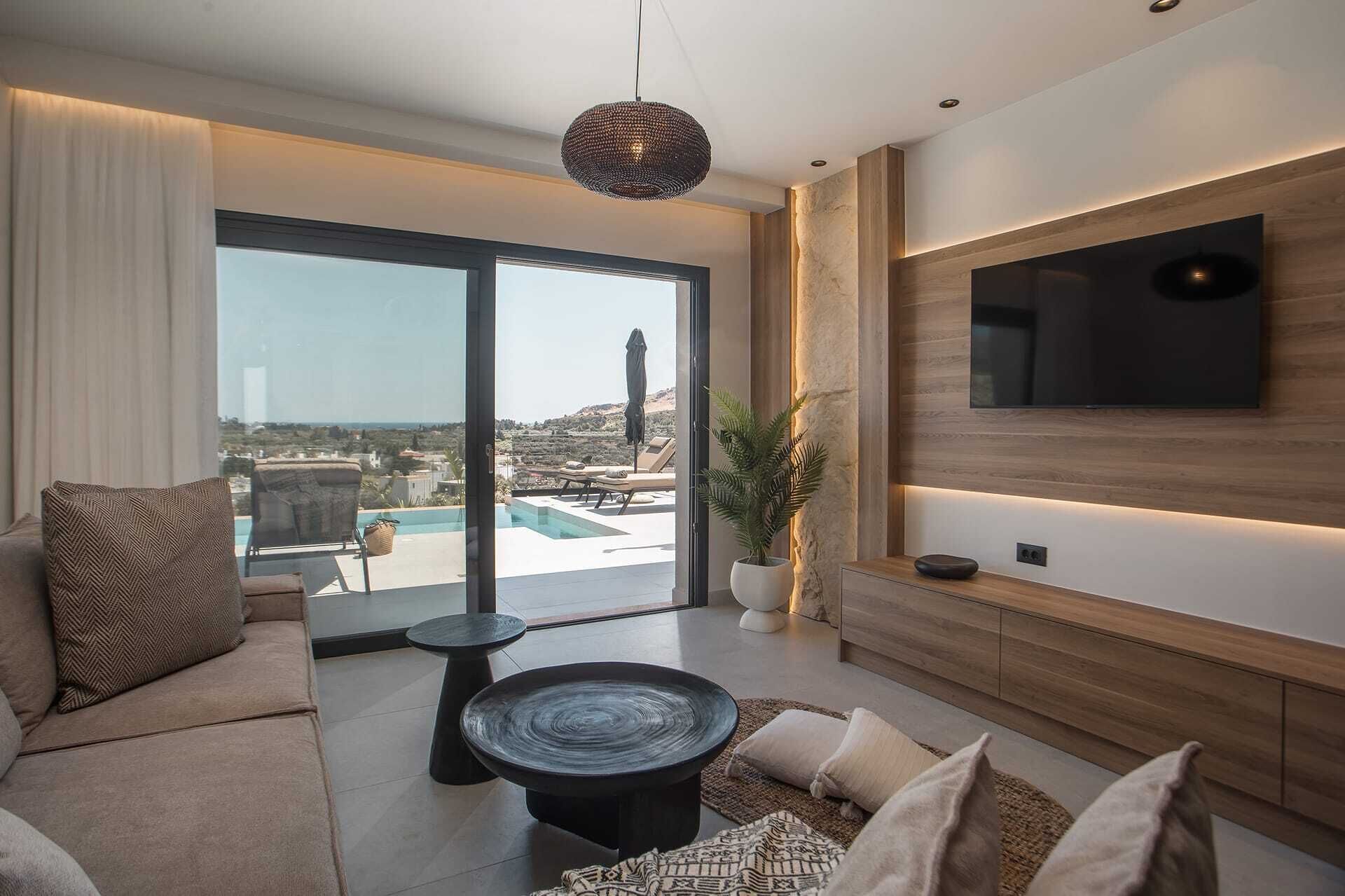 Un salon moderne doté d’un grand téléviseur, offrant une vue sur la piscine et comprenant un coin salon confortable.