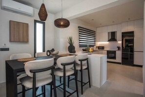 Eine moderne Küche mit weißen Schränken, einer zentralen Kochinsel und Pendelleuchten.