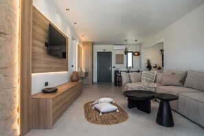 En moderne stue med sofa, sofabord og fjernsyn ophængt på en trævæg.
