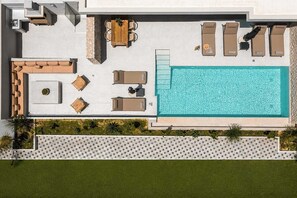 An aerial view of a poolside area with a rectangular pool, multiple lounge chairs, a wooden table, and a small seating area. - Celeste Luxury Villas | Villa Gea, Villa (Rhodes)
