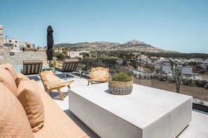 A rooftop terrace with a pool, lounge chairs, a coffee table, and a view of a town and hills. - Celeste Luxury Villas | Villa Gea, Villa (Rhodes)