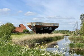 Een modern gebouw met een opvallend uitkragend ontwerp boven water, omgeven door een natuurlijke omgeving.