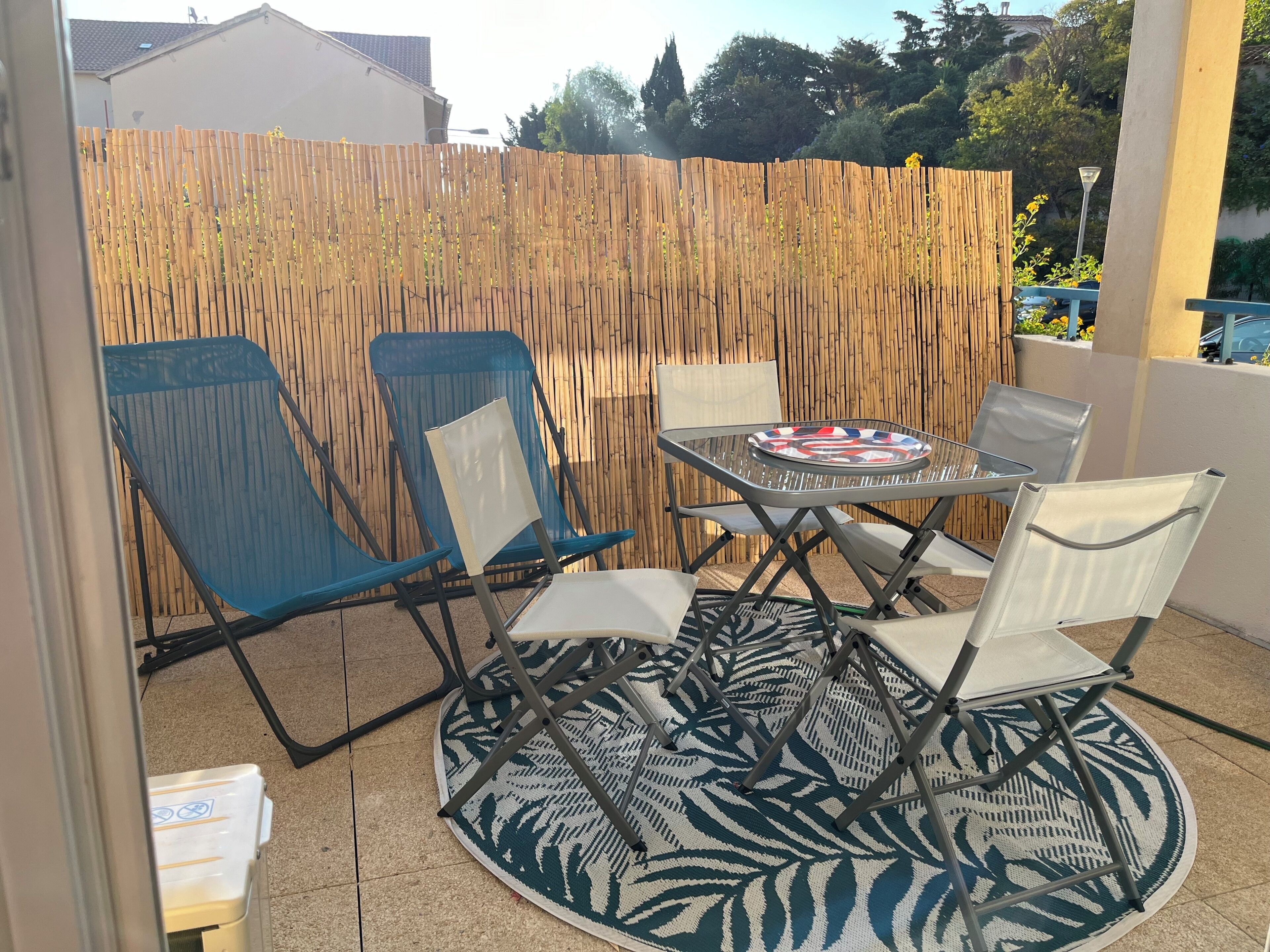 A patio with a round table, four chairs, and a patterned rug.