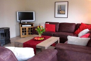 Ein Wohnzimmer mit Sofa, Couchtisch, Fernseher und Kamin.