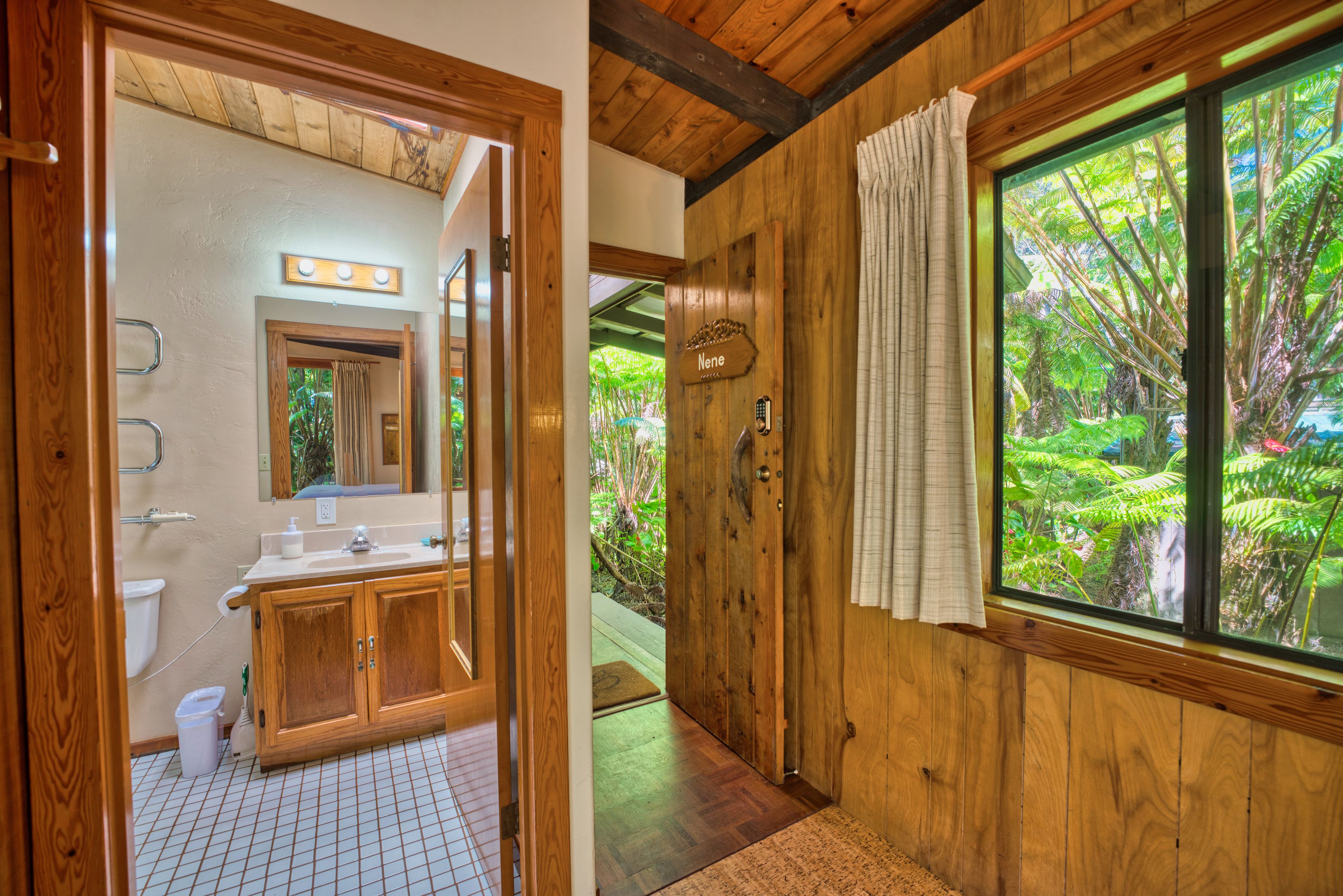 A wooden bathroom with a toilet, sink, and mirror.