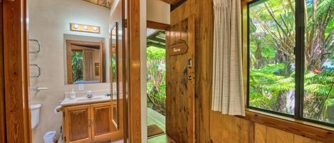 A wooden bathroom with a toilet, sink, and mirror.