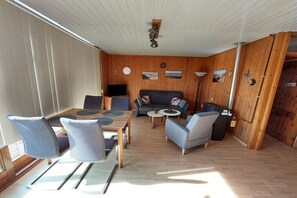 Ein Zimmer mit Esstisch, Stühlen, einer Couch und einem Fernseher.