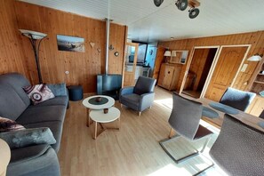 Ein gemütliches Wohnzimmer mit einer Couch, Sesseln, einem Couchtisch und einem Essbereich mit Stühlen.