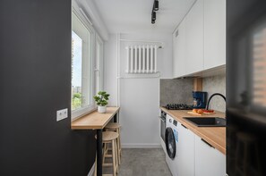 Une cuisine compacte équipée d’un lave-linge intégré, d’une fenêtre et d’un radiateur.