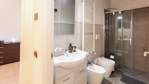 A bathroom with a white sink, a toilet, a glass shower enclosure, and a mirror.