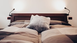 A bed with a wooden headboard, two bedside lamps, and a white pillow.