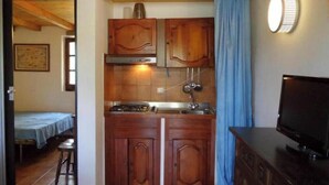 Cocina pequeña con armarios de madera, estufa y pileta.