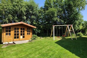 Eine Holzhütte mit Veranda und einer Schaukel im grünen Garten.