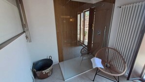 Une salle de bain moderne avec une douche à parois de verre, une chaise en osier et un seau.