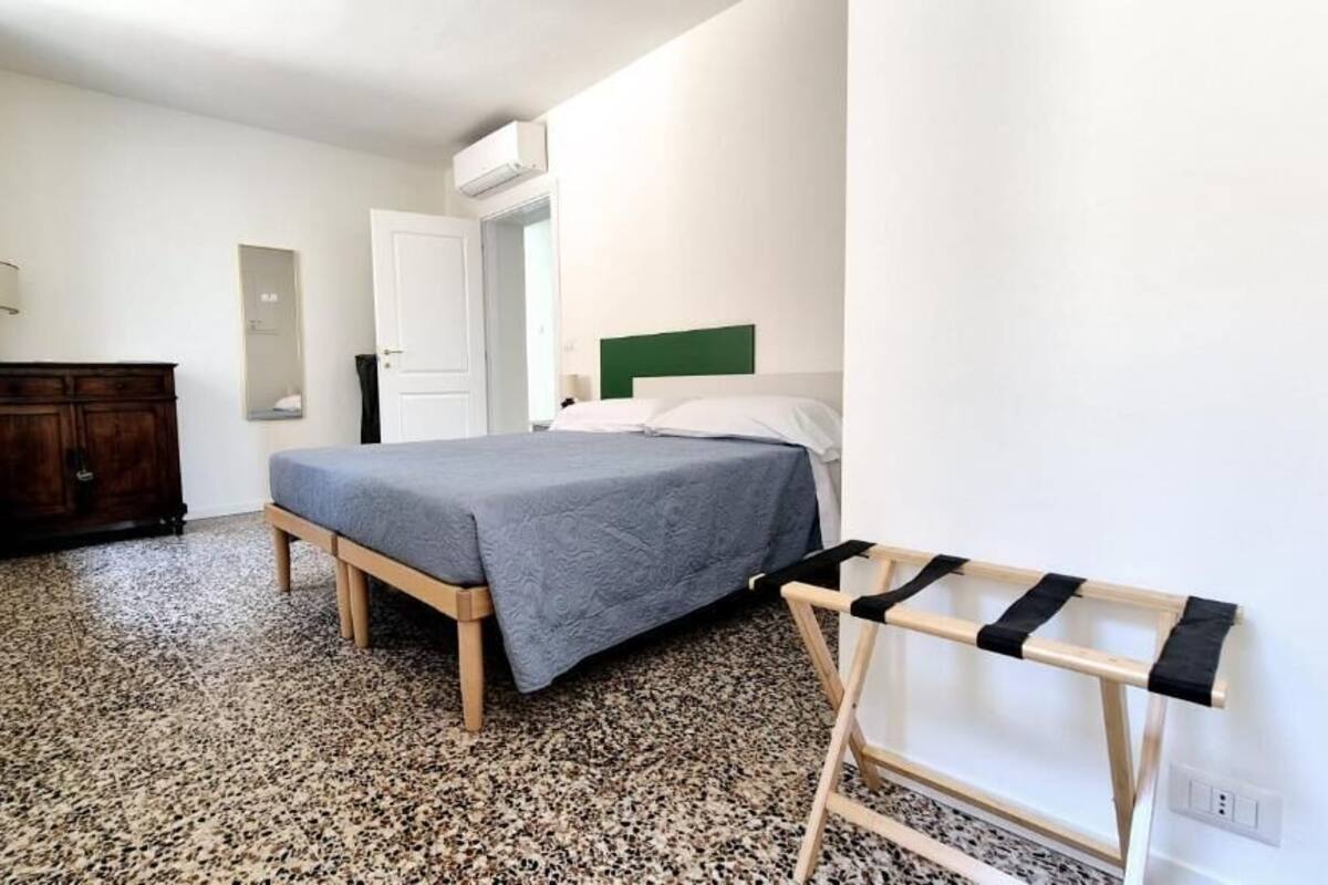 A bedroom with a bed, a wooden bench, a small table, and a wardrobe.