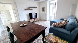 Una sala de estar con una mesa de madera, un sofá azul, un televisor y un radiador.