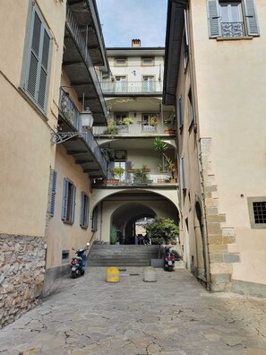 Una calle estrecha con adoquines, un pasaje cubierto y dos scooters estacionados.