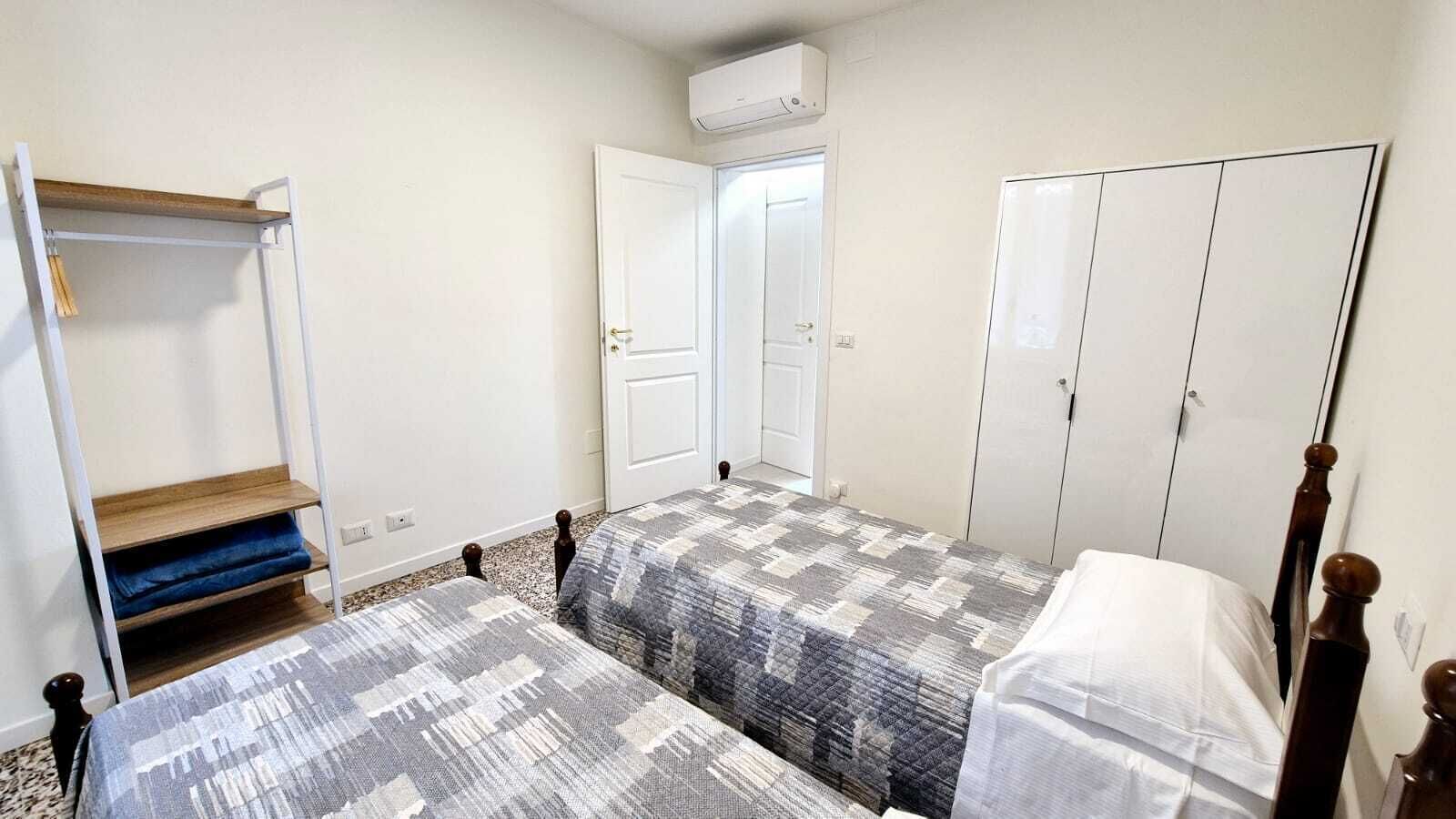Un dormitorio con dos camas, un armario, una puerta y una estantería.