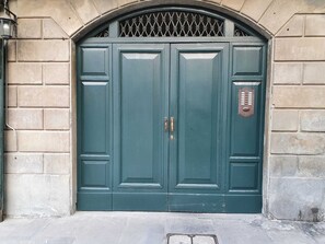 Una puerta doble con una celosía metálica, un pomo de latón y una cerradura.