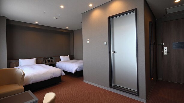 Habitación de hotel con dos camas, un sofá, un escritorio y un armario.