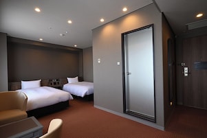 Une chambre d’hôtel avec deux lits, un canapé, un bureau et une armoire.