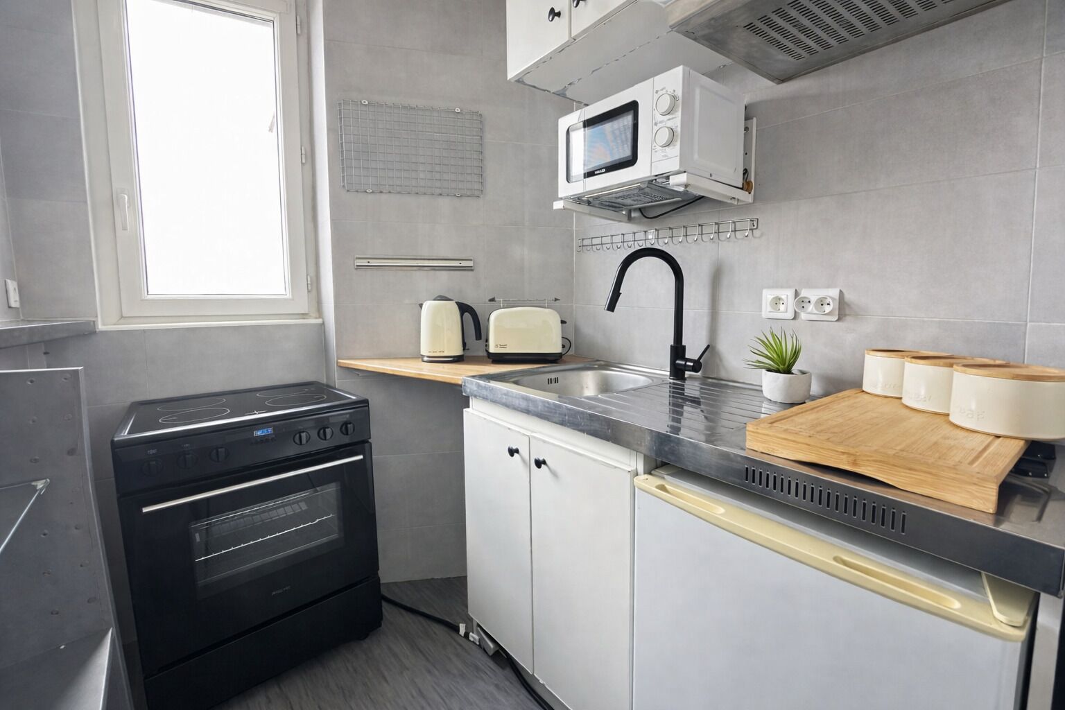 Une cuisine moderne équipée d’un four encastré, d’un micro-ondes, d’un évier et d’une planche à découper en bois.