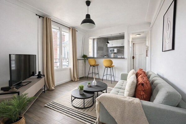 A modern living room with a sofa, TV, and dining area. - Luxueux 2 pièces près du Parc Monceau (Paris)