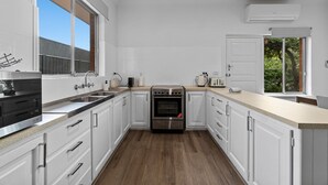 A modern kitchen with white cabinets, stainless steel appliances, and a large window. - Spacious 3-Bed Home in Payneham South (Payneham South)