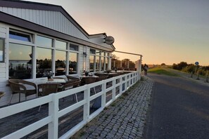 Ein Restaurant mit Außenbereich, einem weißen Zaun und Blick auf das Wasser.