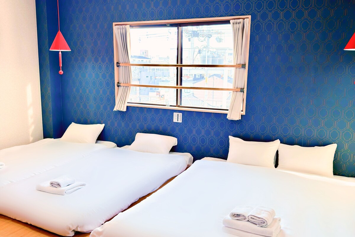 A hotel room with two beds, a window with curtains, and a red hanging light fixture.