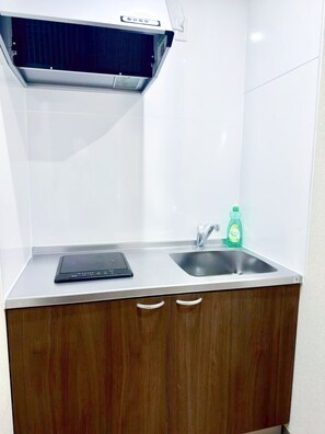 A kitchen with a built-in induction cooktop, a stainless steel sink, and a green dish soap bottle. - Dc桜の苑-The Residence Tsurumibashi Shopping Arcade (Osaka)