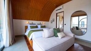 A bedroom with a bed, a sofa, a mirror, and a view of the outside. - K Club Cemagi Villa 7 (Badung)