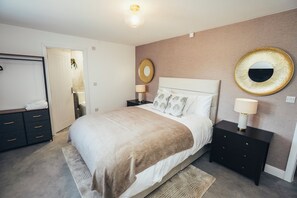 Ein Schlafzimmer mit einem Bett, Nachttischen, einem Schminktisch und einem Spiegel.