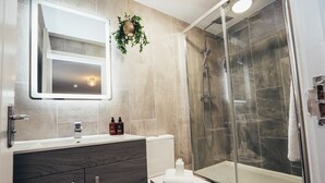 Een moderne badkamer met toilet, wastafel en douche.