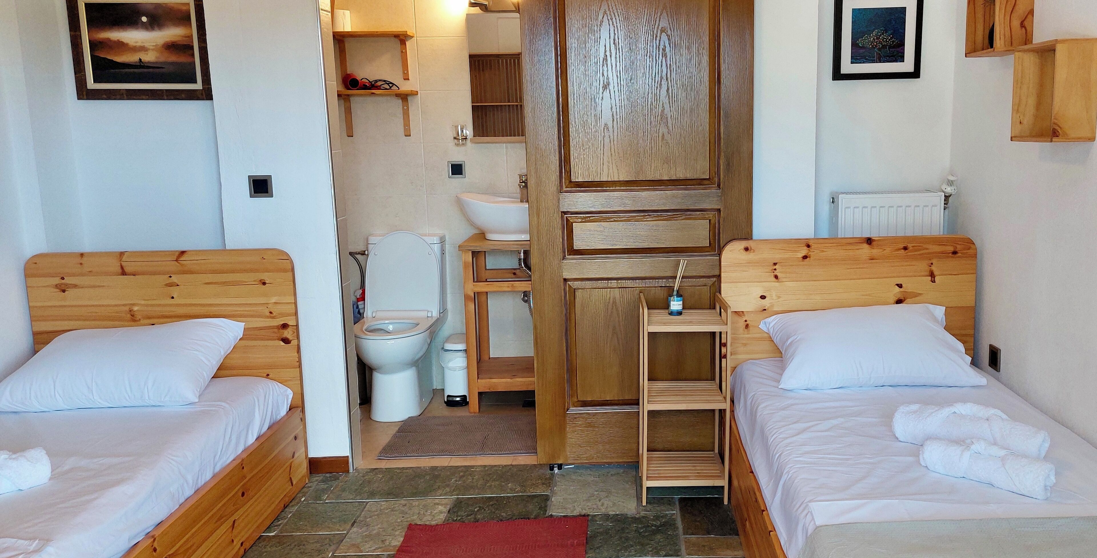 Ein Schlafzimmer mit zwei Holzbett, einem Holzschrank, einer weißen Toilette und einem Waschbecken.